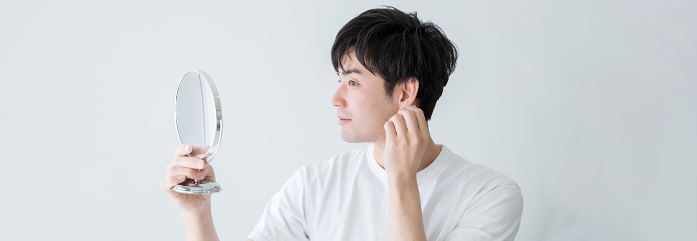 man looking at ears in mirror