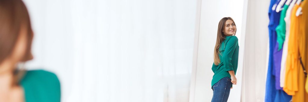 woman looking at her body in the mirror and smiling